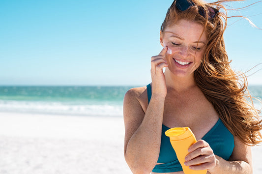 Woman applying sun cream on a beach in hot weather.
