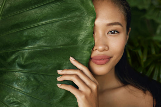 Woman behind a plant used in vegan skincare products.